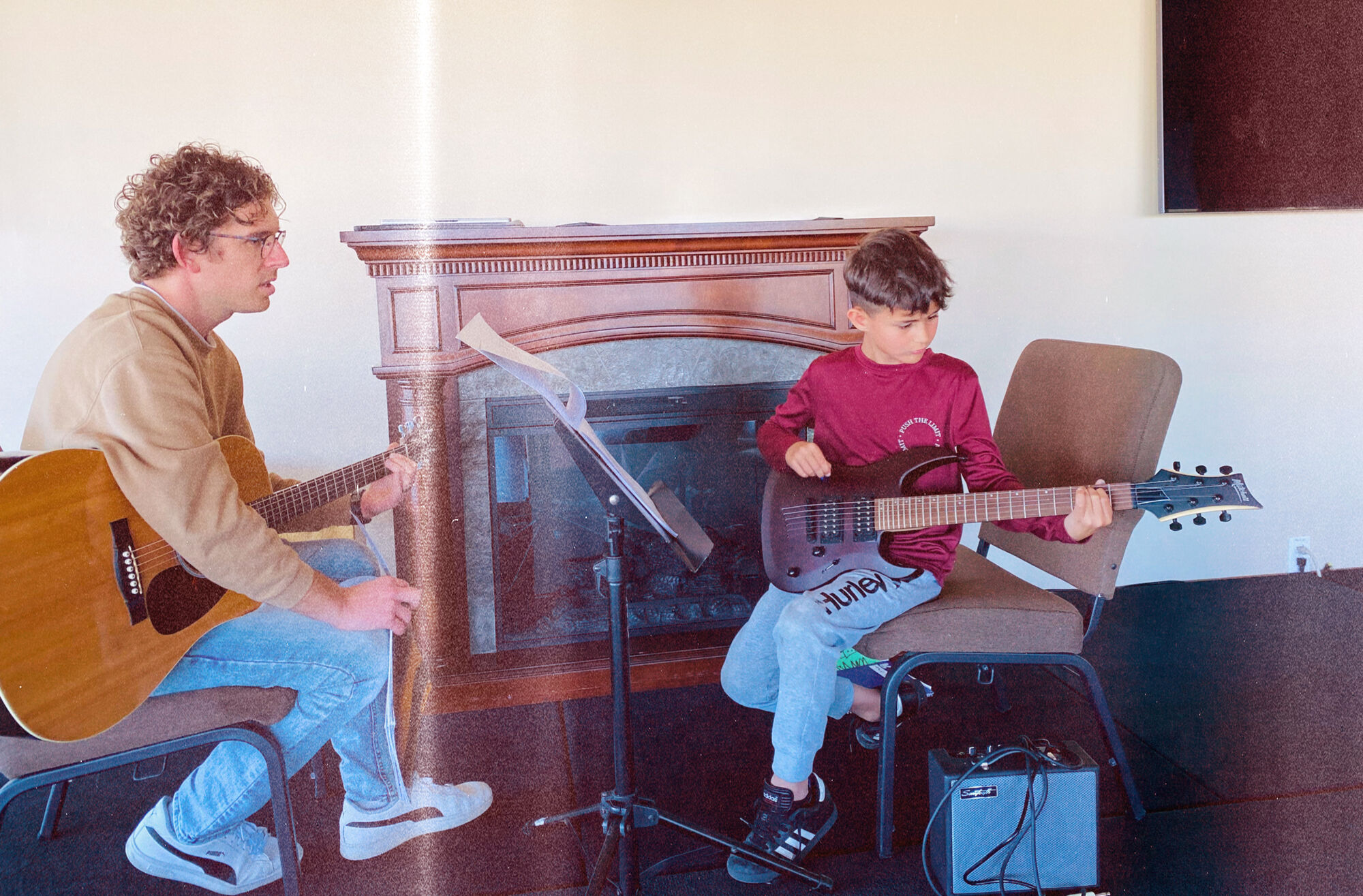 Michael Schirner teaching a young student to play electric guitar with an amp